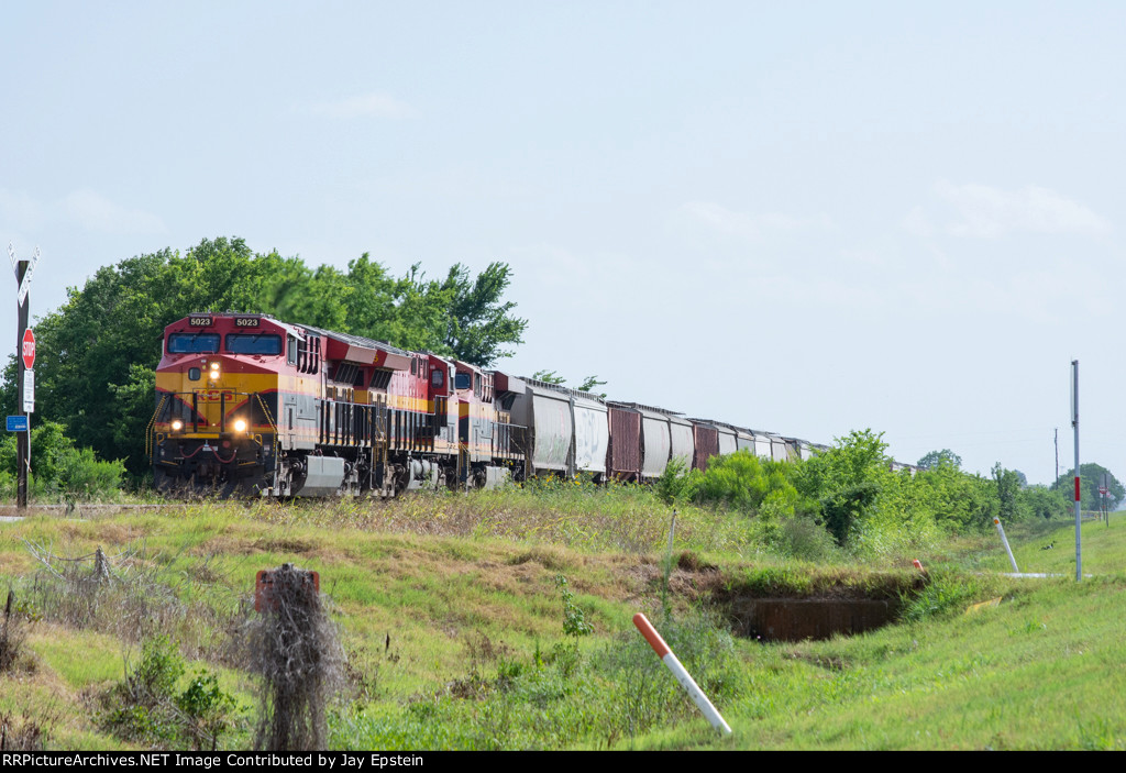 A northbound grain train approaches a small crossing